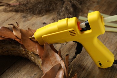 Photo of Hot glue gun and craft on wooden table, closeup