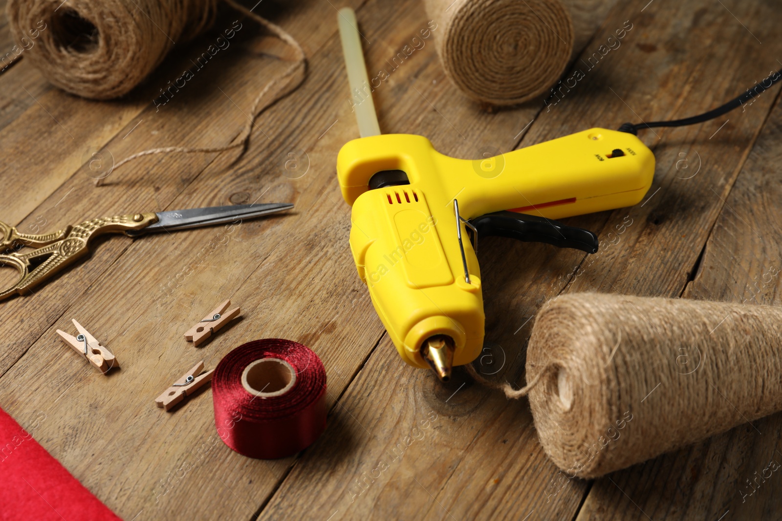 Photo of Hot glue gun and handicraft materials on wooden table