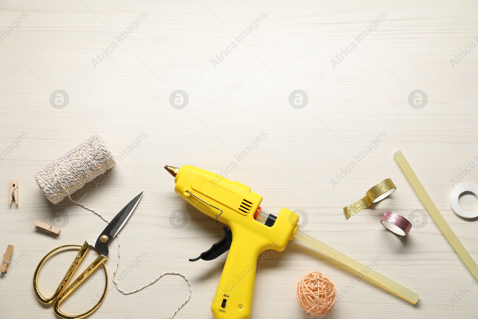 Photo of Hot glue gun and handicraft materials on white wooden table, flat lay. Space for text