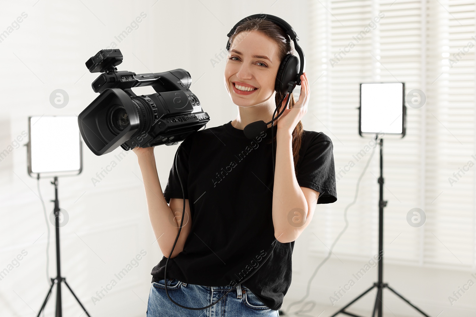 Photo of Happy woman with professional video camera and headset in studio