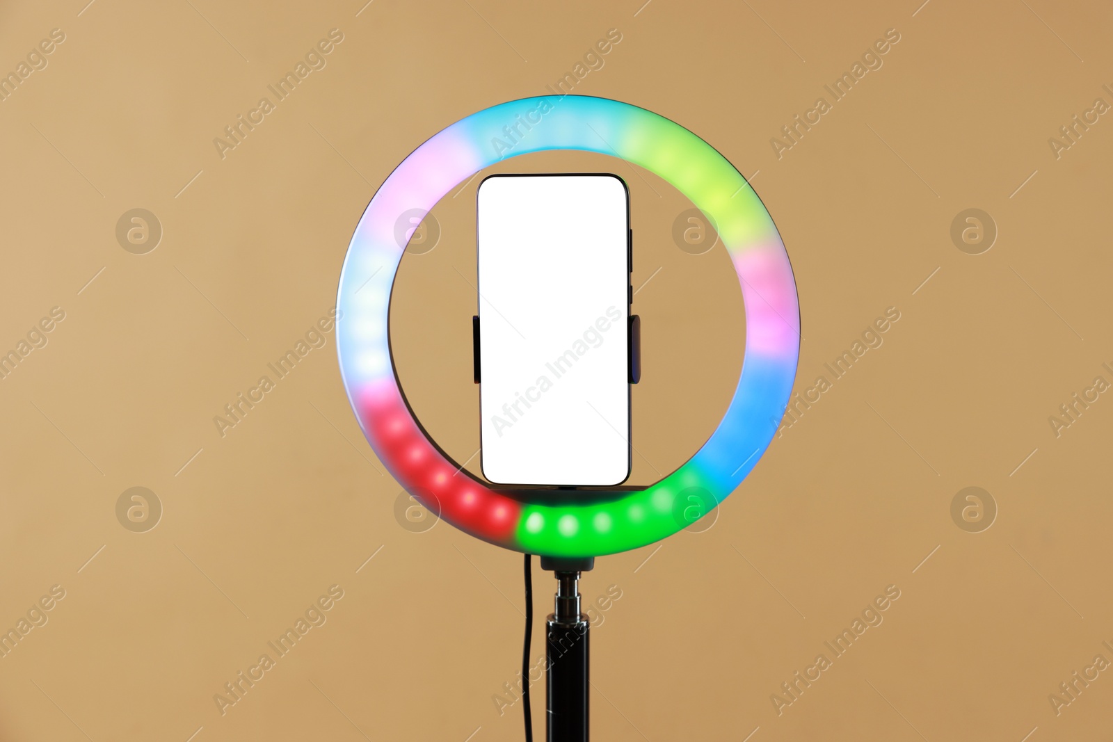 Photo of Ring lamp with smartphone on beige background