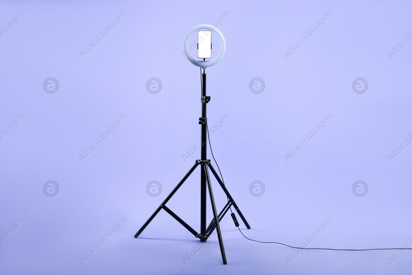 Photo of Ring lamp with smartphone on purple background