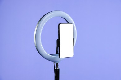 Photo of Ring lamp with smartphone on purple background