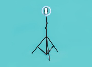 Photo of Ring lamp with smartphone on light blue background