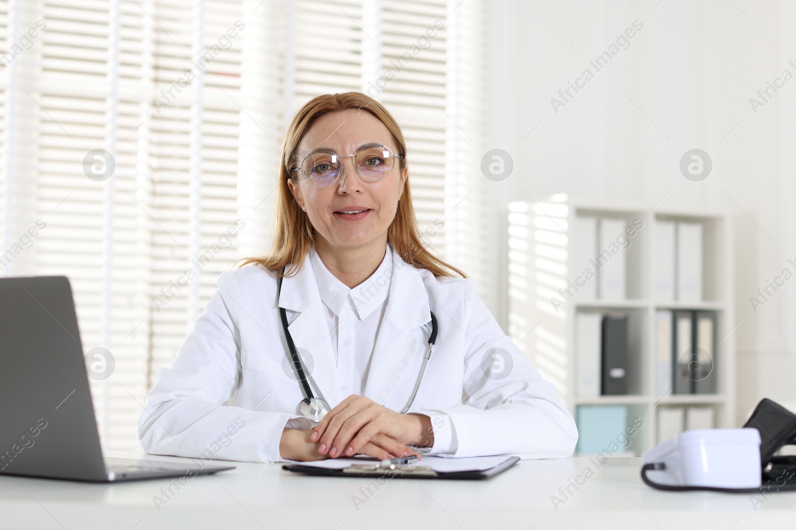 Photo of Cardiologist with stethoscope at white table in clinic