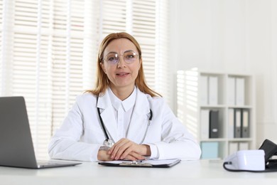 Cardiologist with stethoscope at white table in clinic