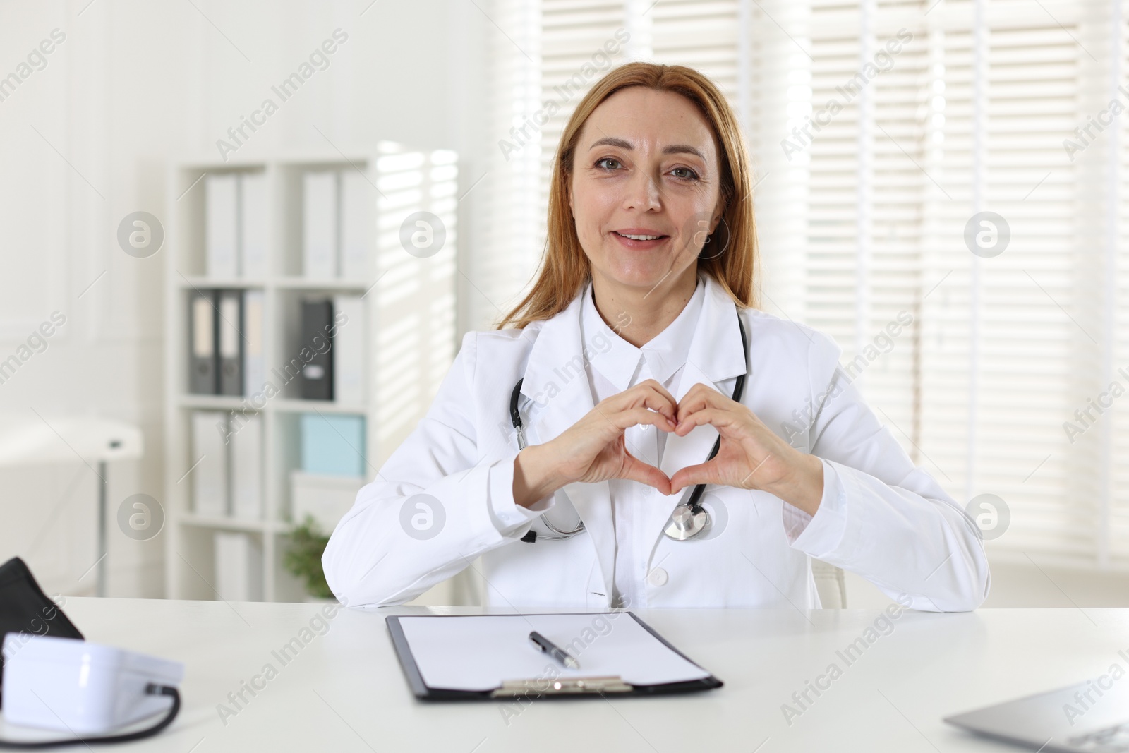 Photo of Cardiologist making heart with hands indoors, closeup