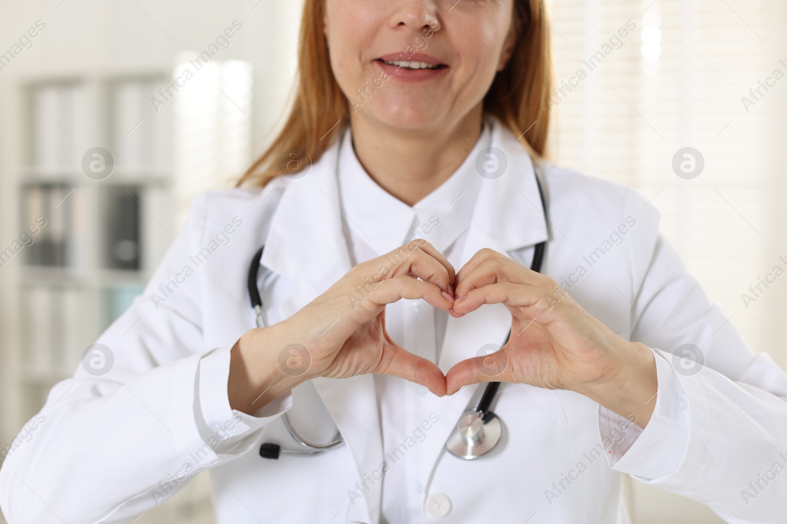 Photo of Cardiologist making heart with hands in hospital, closeup