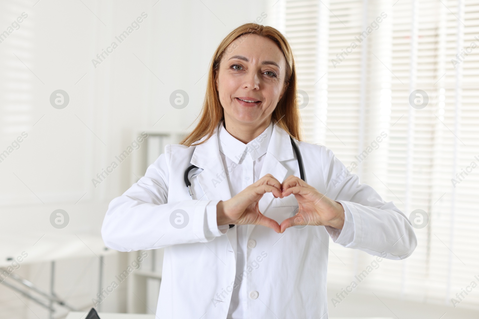 Photo of Cardiologist making heart with hands in hospital