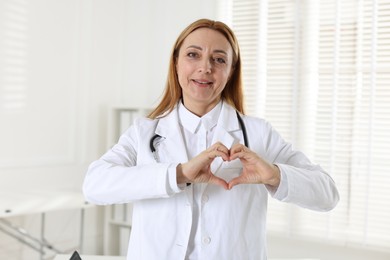 Cardiologist making heart with hands in hospital