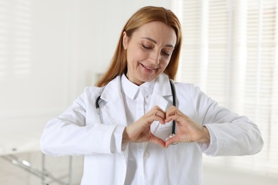 Photo of Cardiologist making heart with hands in hospital