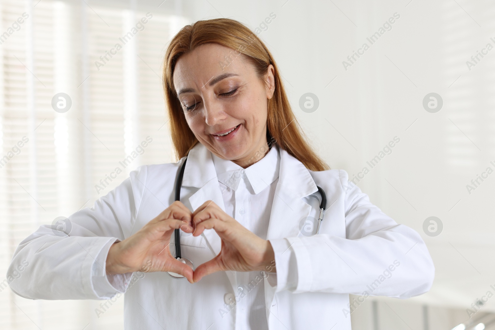 Photo of Cardiologist making heart with hands in hospital