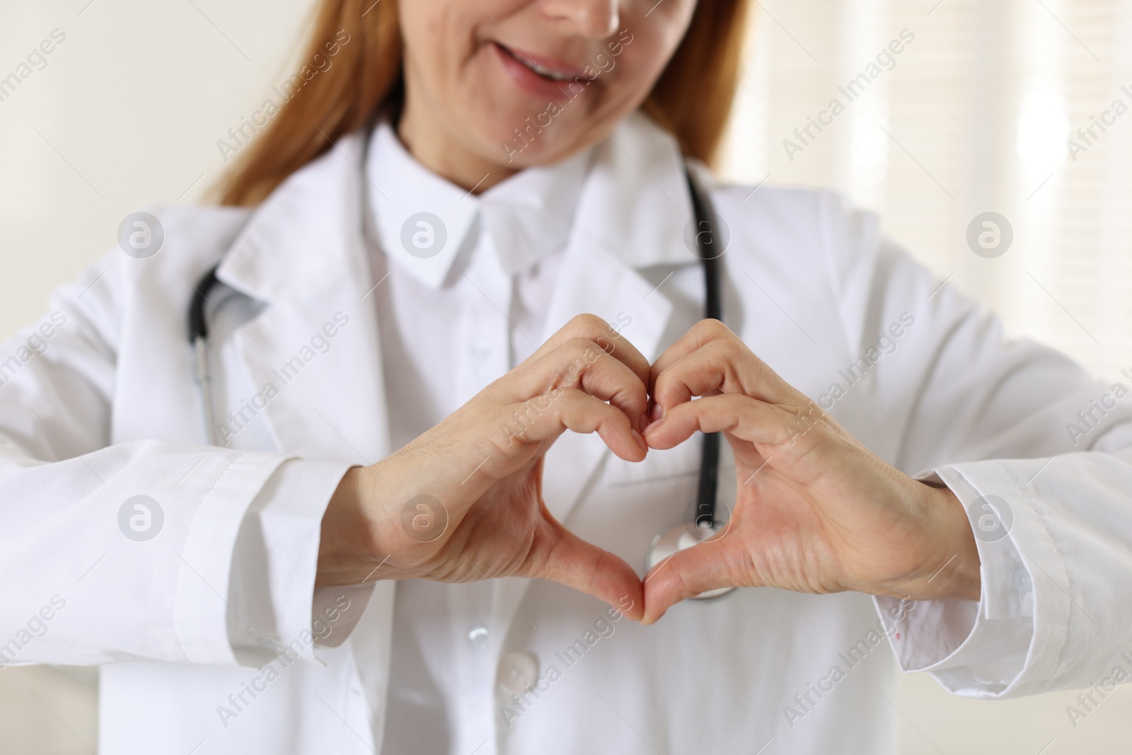 Photo of Cardiologist making heart with hands indoors, closeup