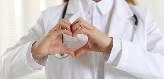 Photo of Cardiologist making heart with hands indoors, closeup