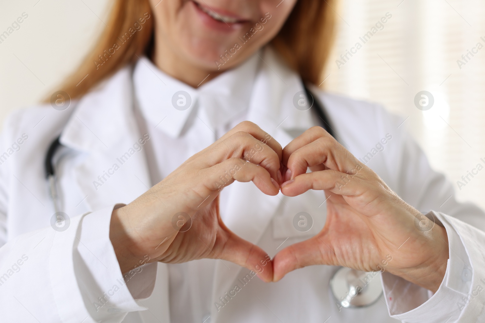 Photo of Cardiologist making heart with hands indoors, closeup