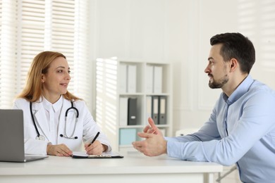 Photo of Man having consultation with cardiologist at desk in clinic