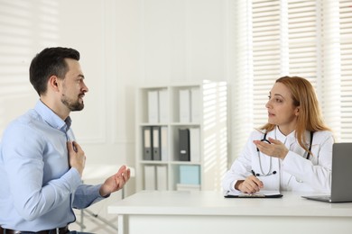 Photo of Man having consultation with cardiologist at desk in clinic