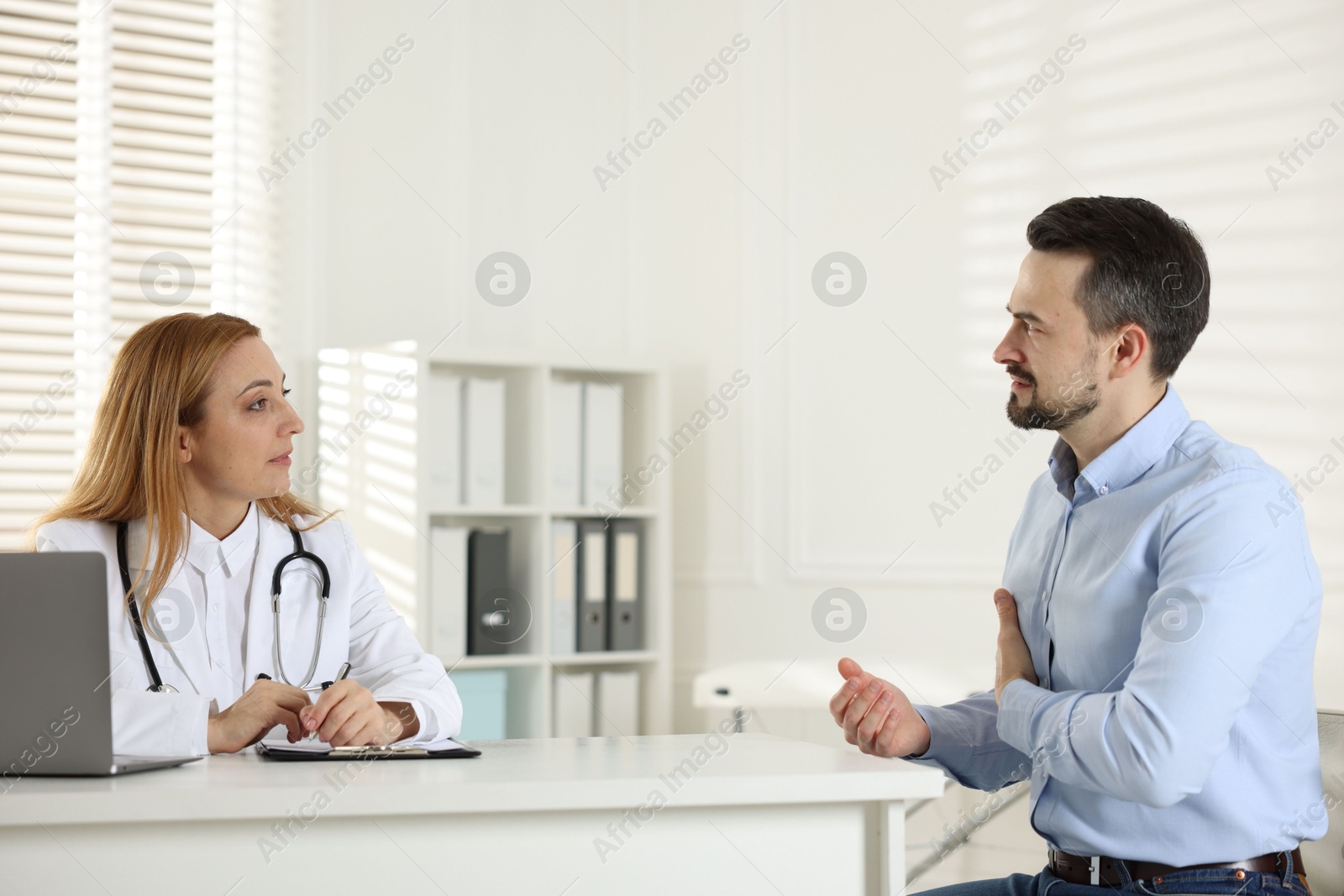 Photo of Man having consultation with cardiologist at desk in clinic