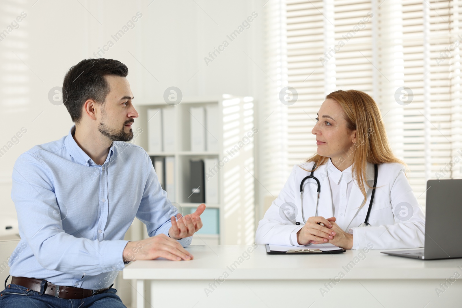 Photo of Man having consultation with cardiologist at desk in clinic