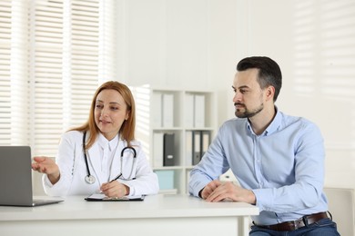 Photo of Man having consultation with cardiologist at desk in clinic