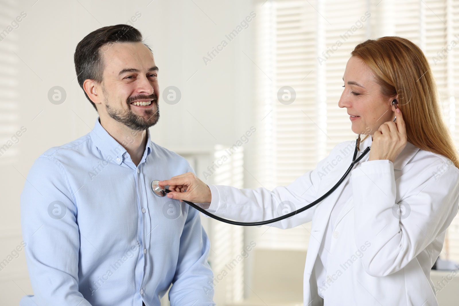 Photo of Cardiologist with stethoscope listening patient's heartbeat in clinic