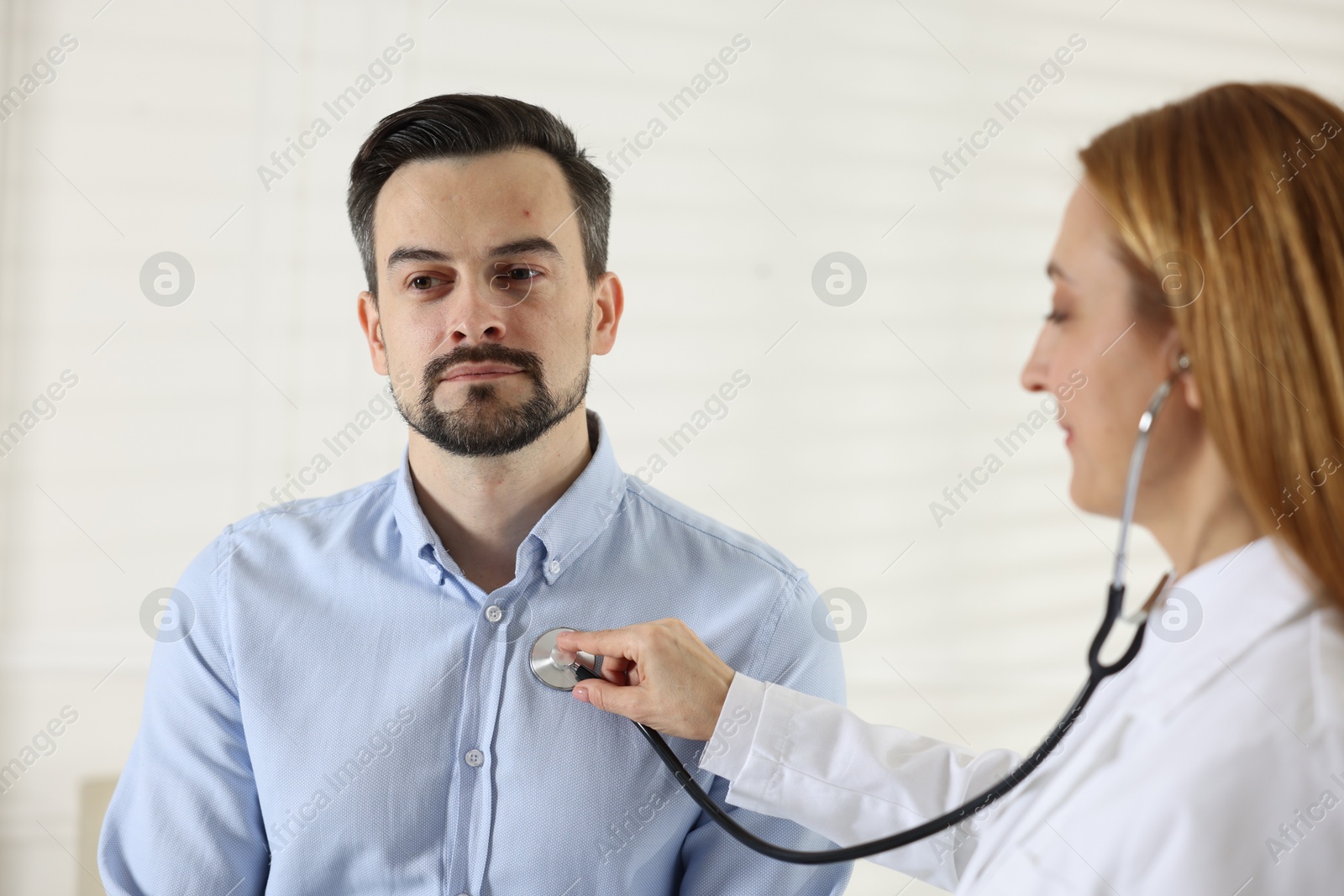 Photo of Cardiologist with stethoscope listening patient's heartbeat in clinic