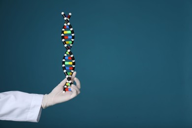 Photo of Scientist holding DNA structure model on dark blue background, closeup. Space for text