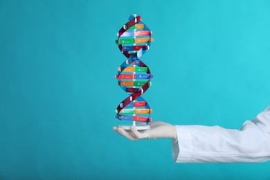 Photo of Scientist holding DNA structure model on light blue background, closeup