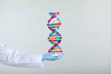 Photo of Scientist holding DNA structure model on white background, closeup