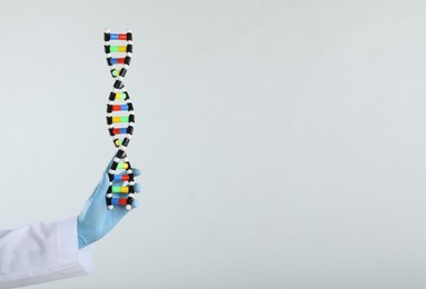 Photo of Scientist holding DNA structure model on white background, closeup. Space for text