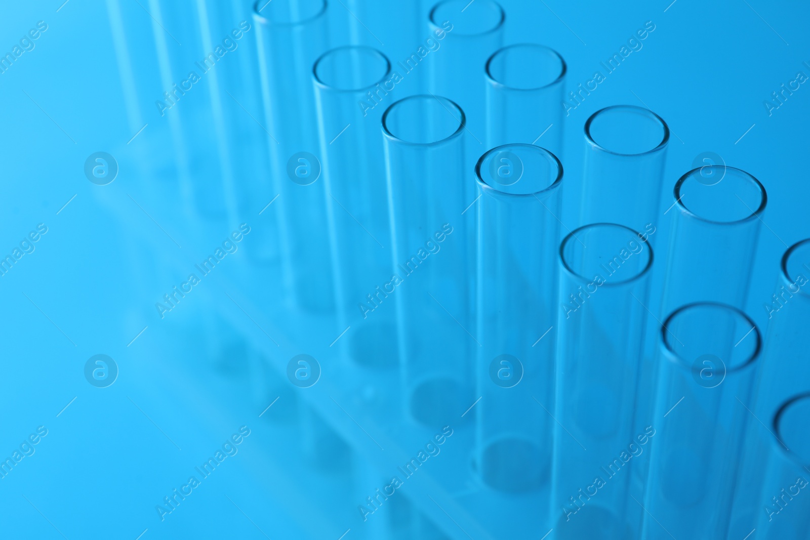 Photo of Empty test tubes on light blue background, closeup. Laboratory glassware