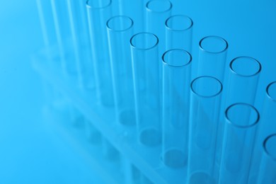 Photo of Empty test tubes on light blue background, closeup. Laboratory glassware