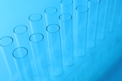 Photo of Empty test tubes on light blue background, closeup. Laboratory glassware