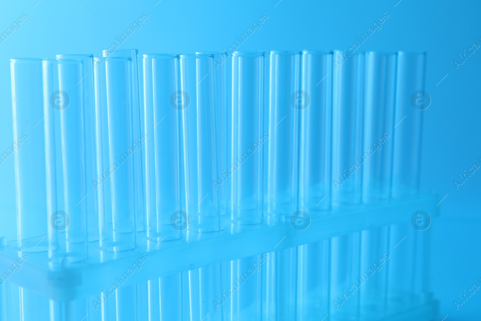 Photo of Empty test tubes on light blue background, closeup. Laboratory glassware