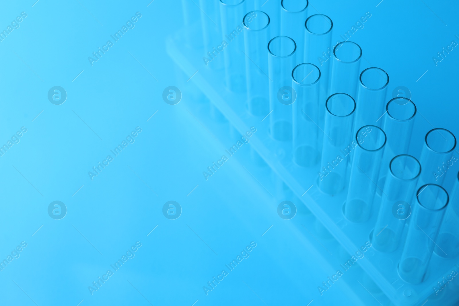 Photo of Empty test tubes on light blue background, space for text. Laboratory glassware