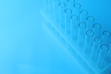 Photo of Empty test tubes on light blue background, space for text. Laboratory glassware