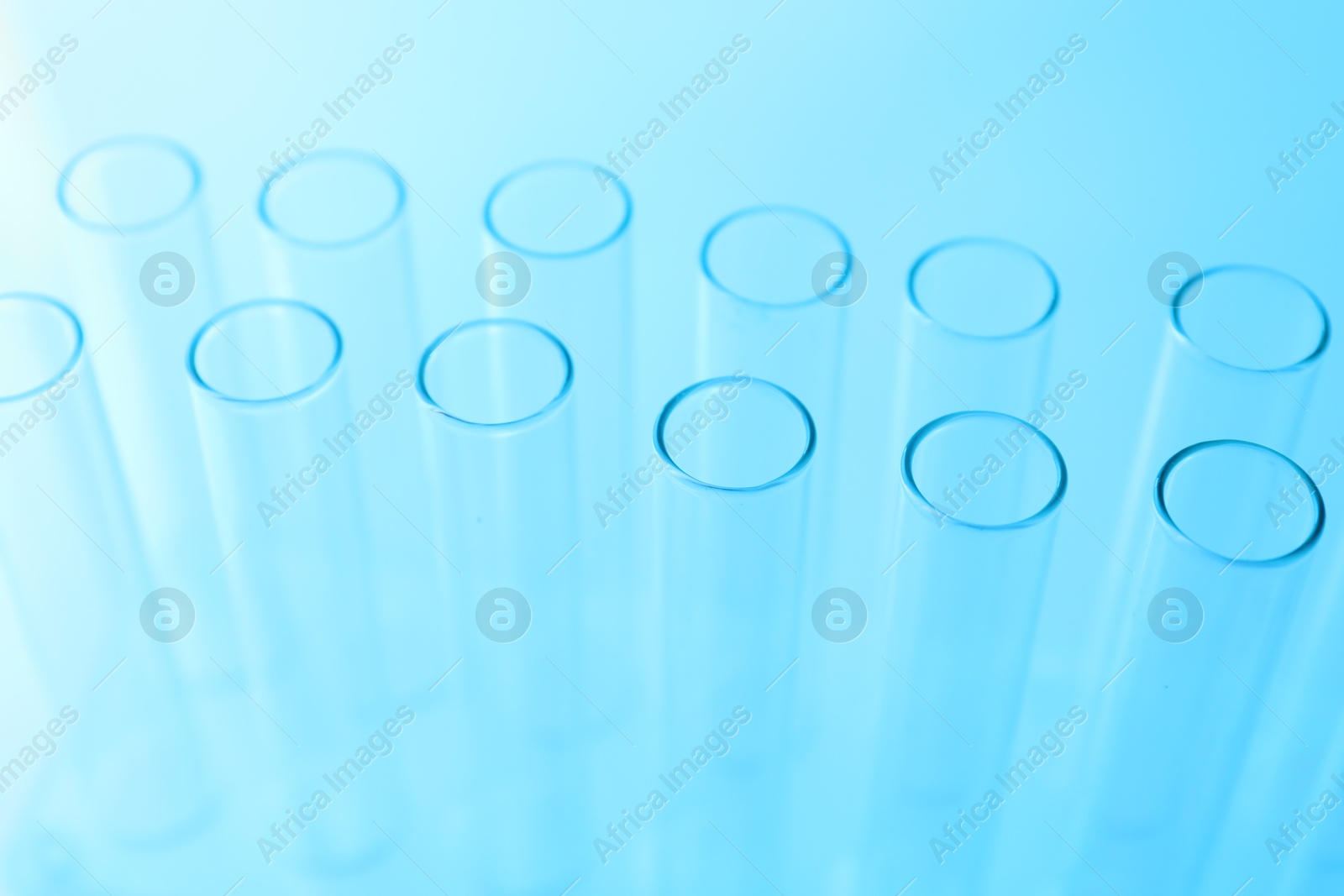 Photo of Empty test tubes on light blue background, closeup. Laboratory glassware