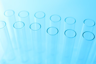 Photo of Empty test tubes on light blue background, closeup. Laboratory glassware