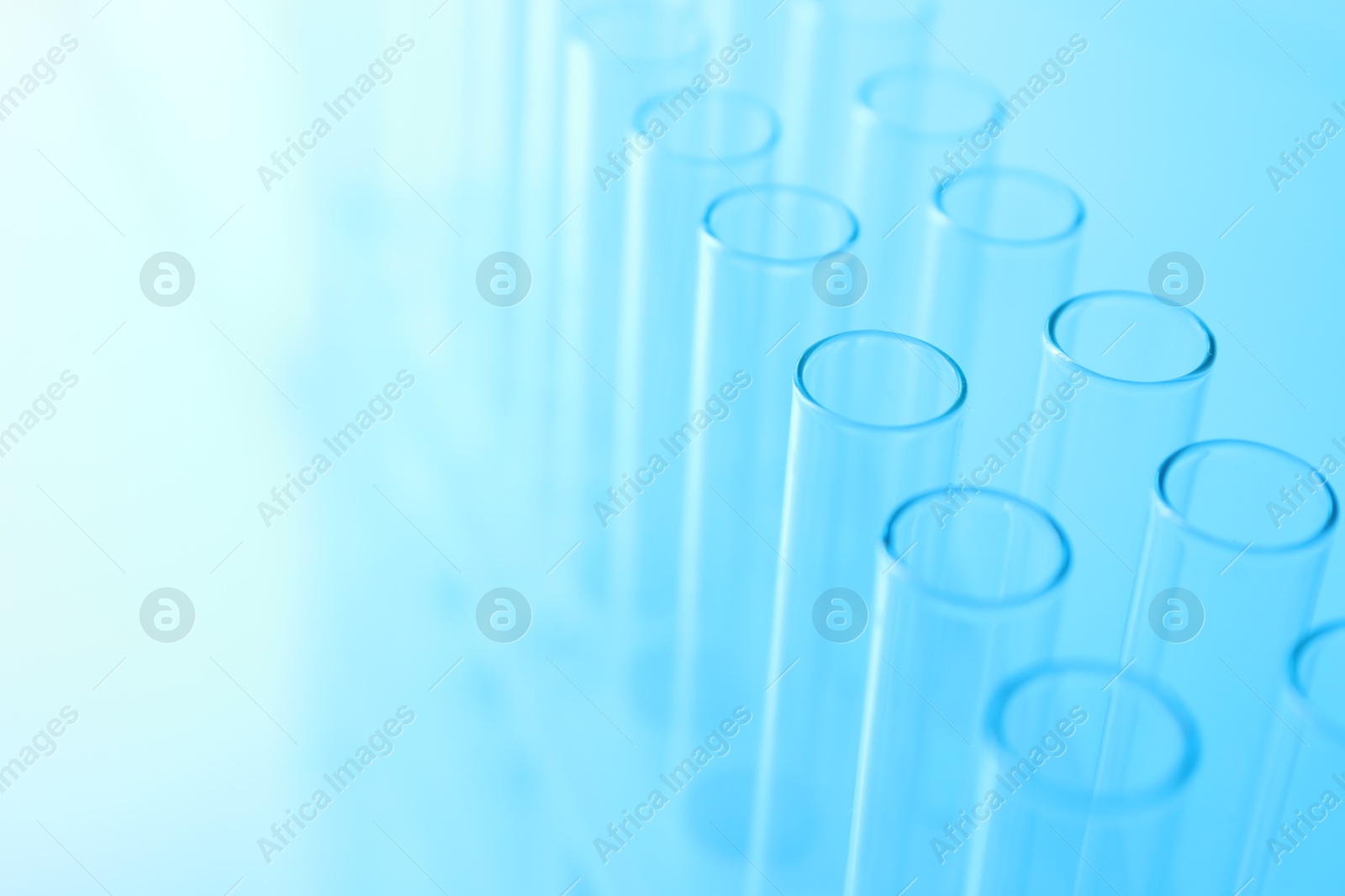 Photo of Empty test tubes on light blue background, closeup. Laboratory glassware