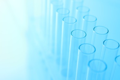 Photo of Empty test tubes on light blue background, closeup. Laboratory glassware