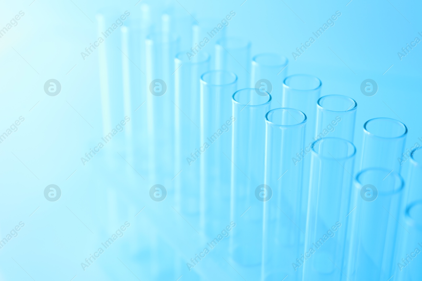 Photo of Empty test tubes on light blue background, closeup. Laboratory glassware