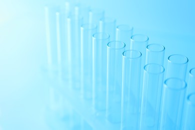 Photo of Empty test tubes on light blue background, closeup. Laboratory glassware