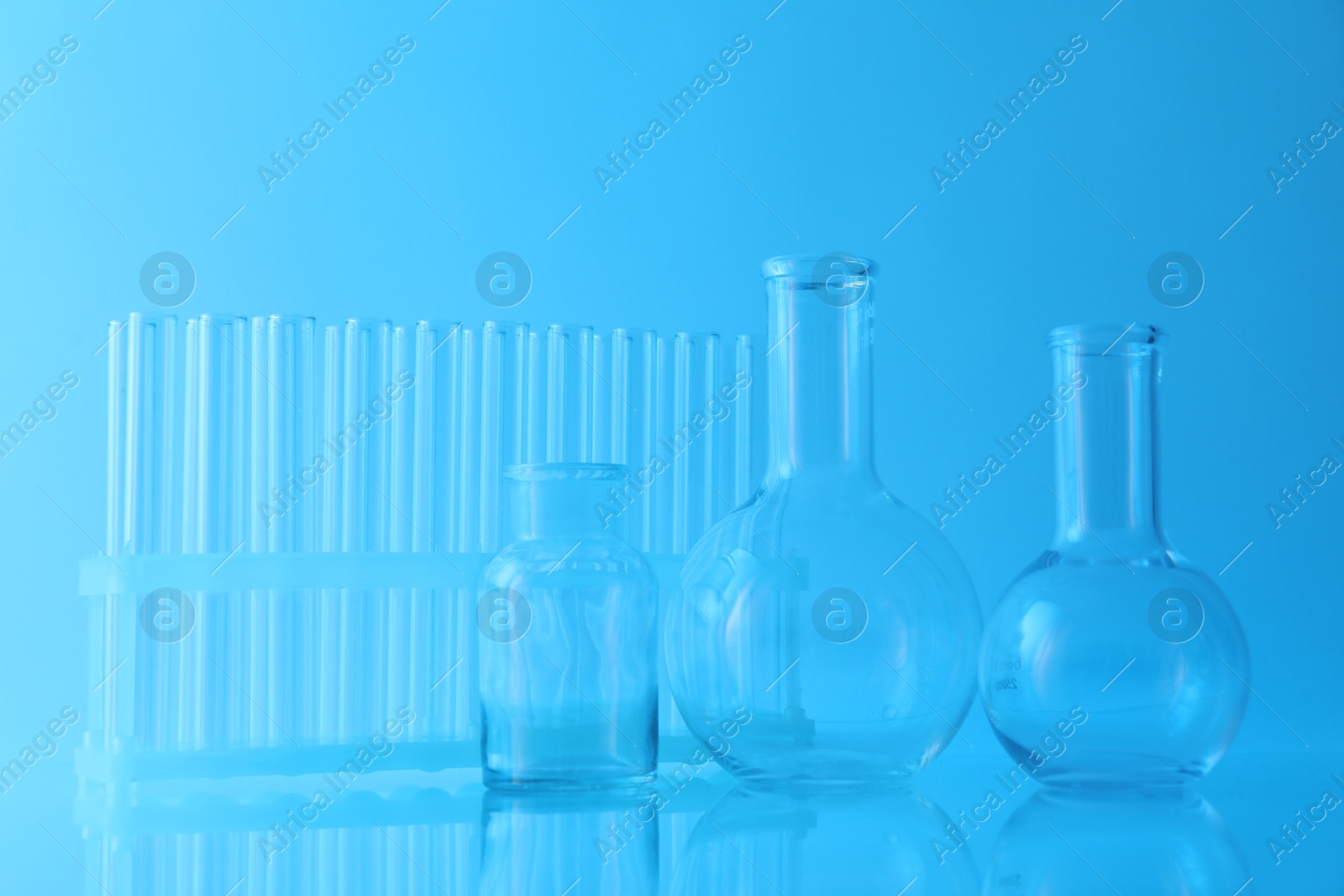 Photo of Different laboratory glassware on light blue background