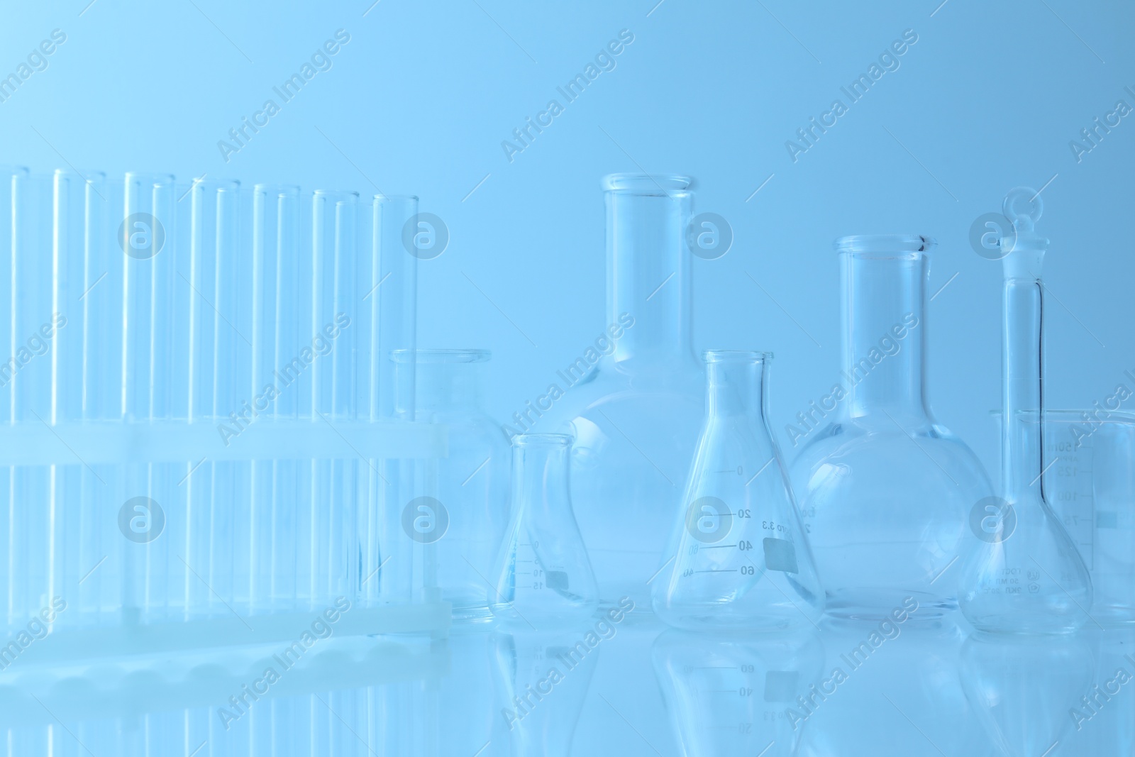 Photo of Different laboratory glassware on light blue background