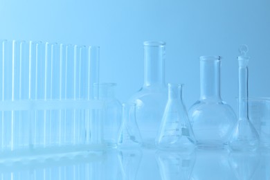 Photo of Different laboratory glassware on light blue background