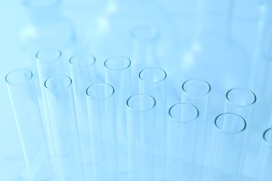 Photo of Empty test tubes on light blue background, closeup. Laboratory glassware