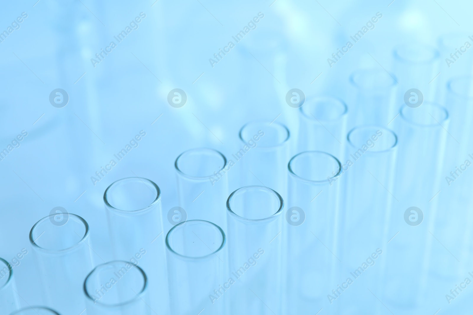 Photo of Empty test tubes on light blue background, closeup. Laboratory glassware