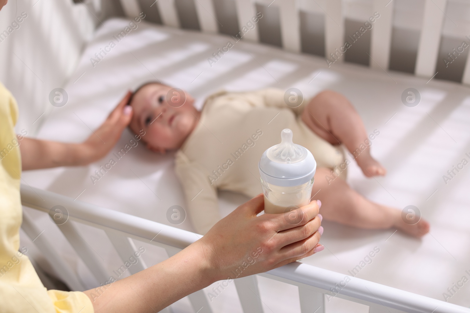 Photo of Mother with feeding bottle of milk near her little baby indoors, above view