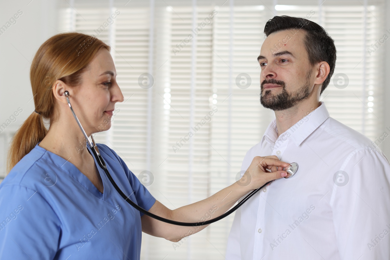 Photo of Cardiologist with stethoscope listening patient's heartbeat in hospital