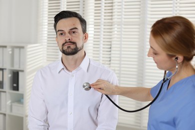 Photo of Cardiologist with stethoscope listening patient's heartbeat in hospital